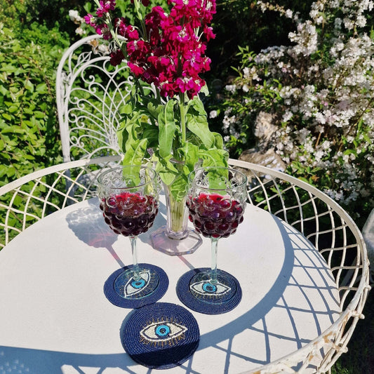 A table with Evil Eye patterned coasters holding glasses of wine