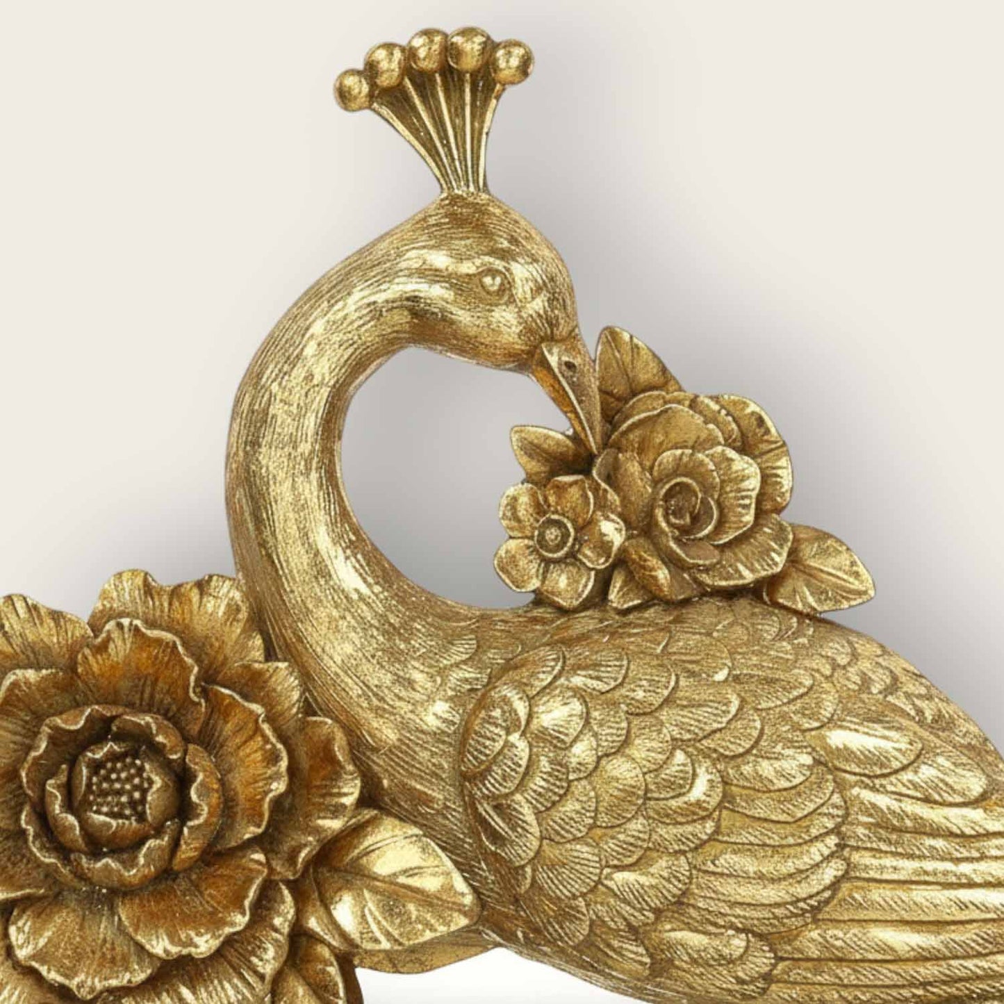 Gold peacock decorative item with floral details on a white background