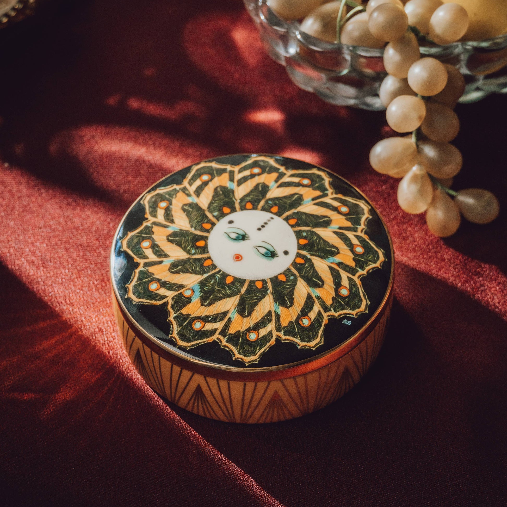 Decorative round box with intricate design on a red fabric background
