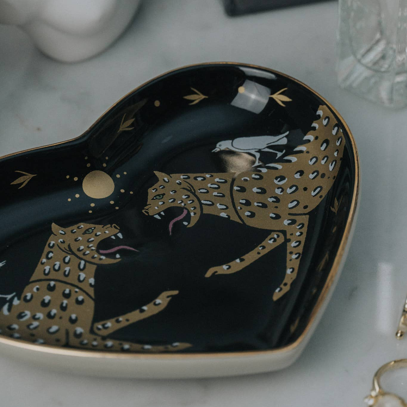 Decorative dish with gold leopard design on a marble surface