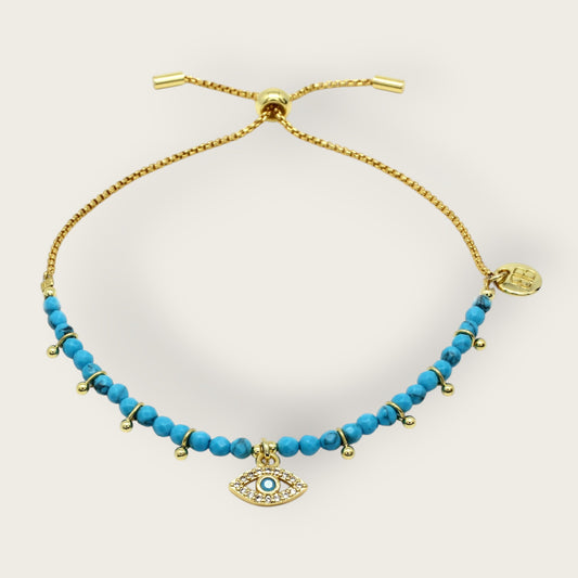 Gold and turquoise beaded bracelet with eye charm on a white background