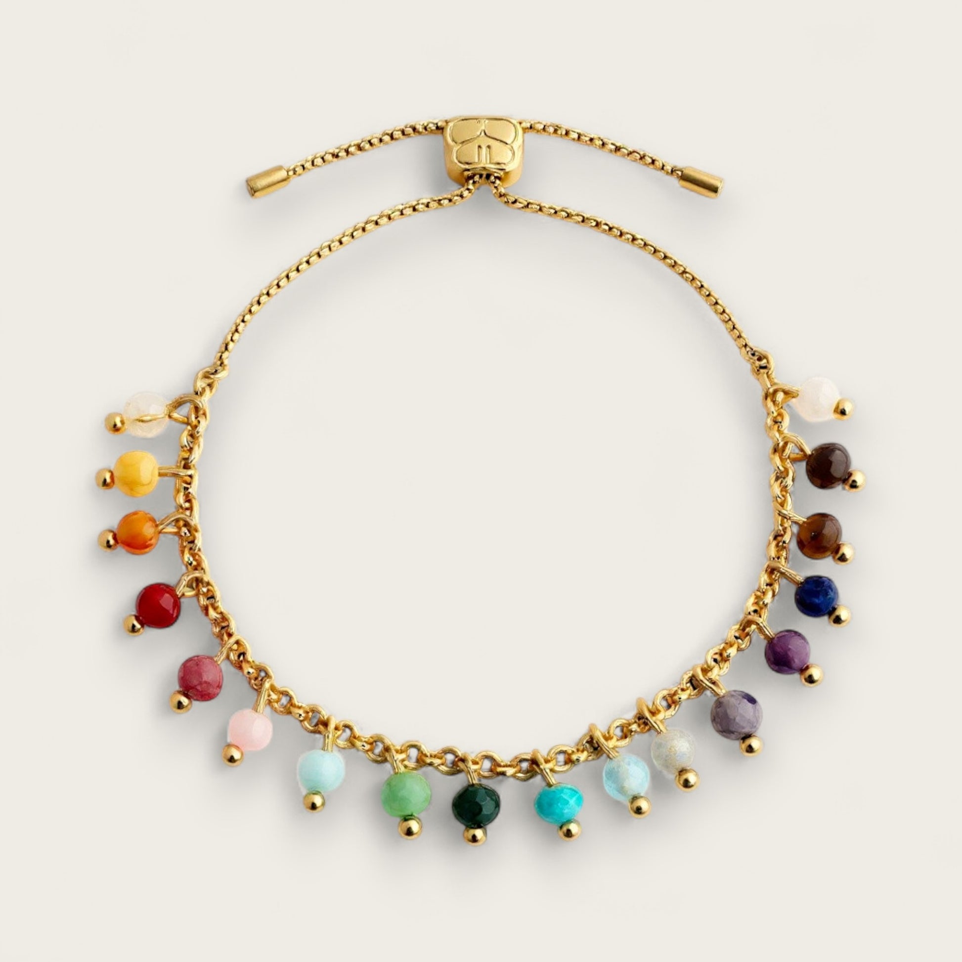 A gold coloured bracelet with multi coloured gem stones running around the edge