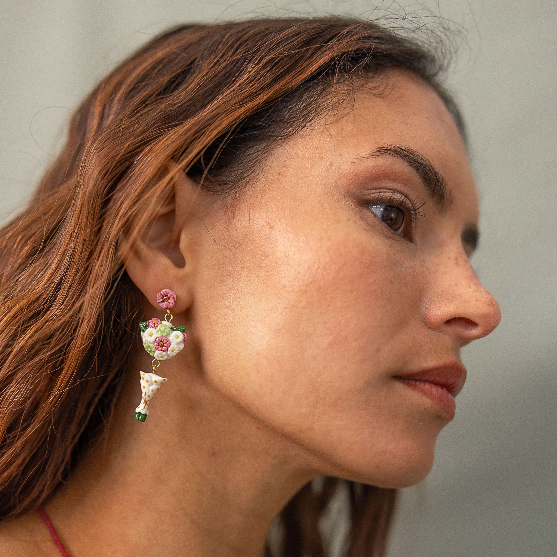 Close-up of a woman wearing floral earrings with a neutral background