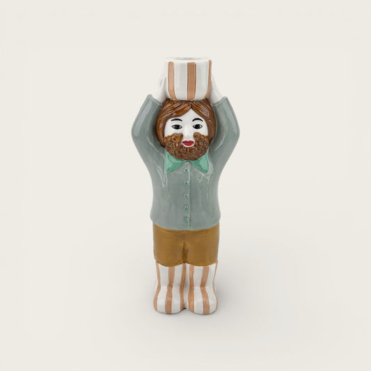 Ceramic figure of a person with a striped hat on a plain background