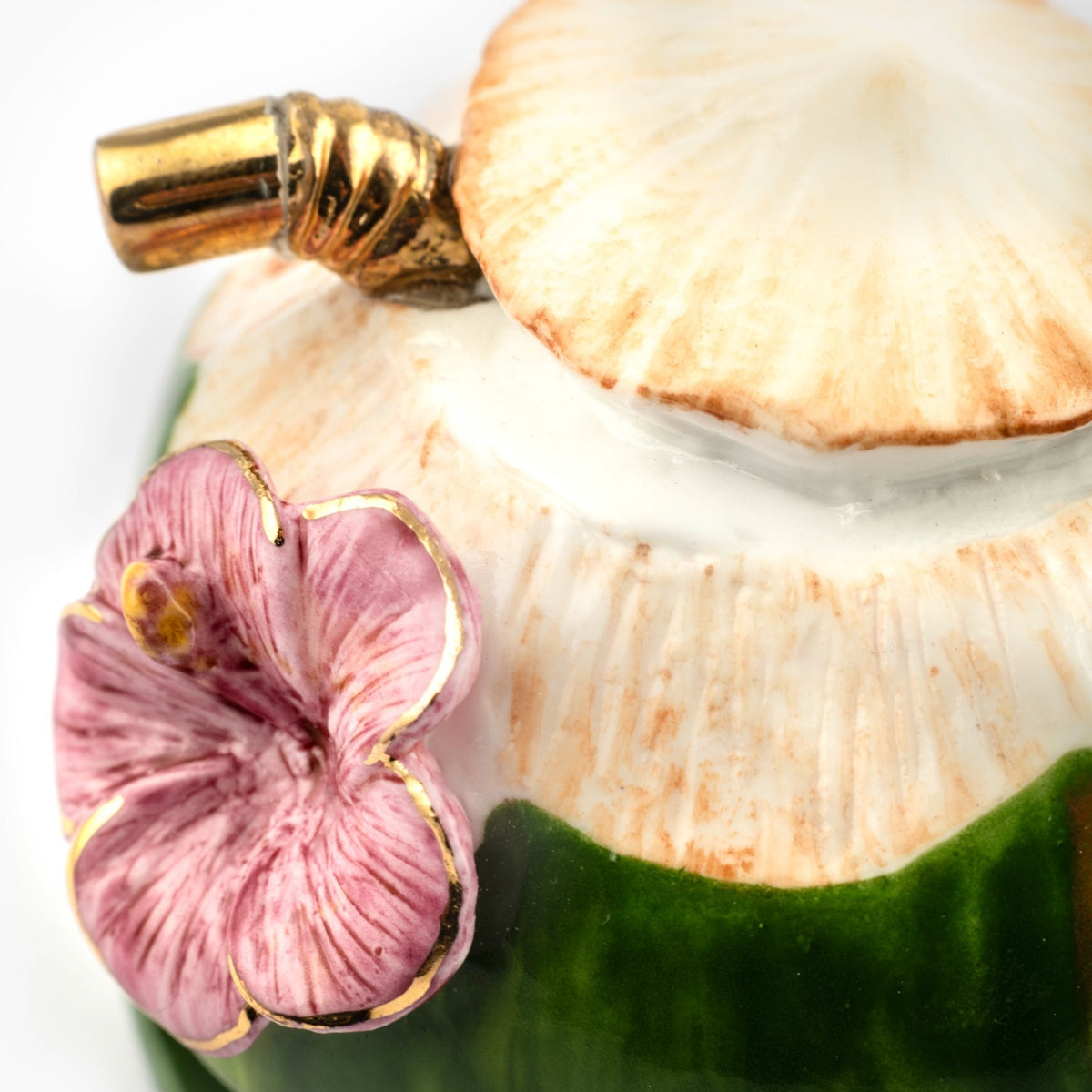 Decorative item with a shell, pink flower, and gold accents on a white background