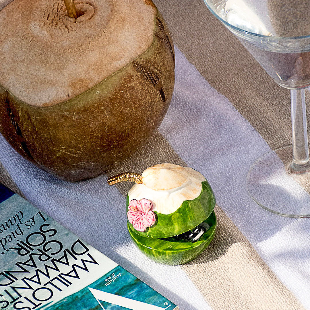 Coconut, small decorative item with a flower, and glass on a table